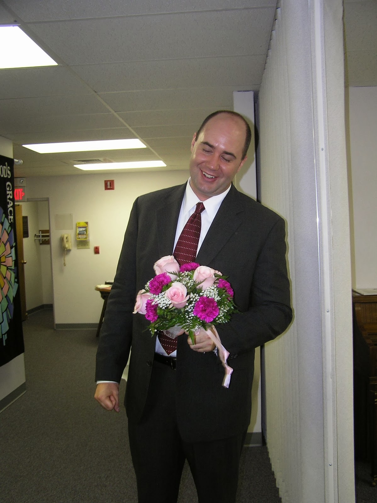 My cousin, in a suit, grinning at the bouquet he just caught.