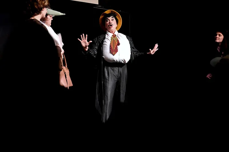 Performer in a pinstripe costume isolated in a warm special on a dark stage