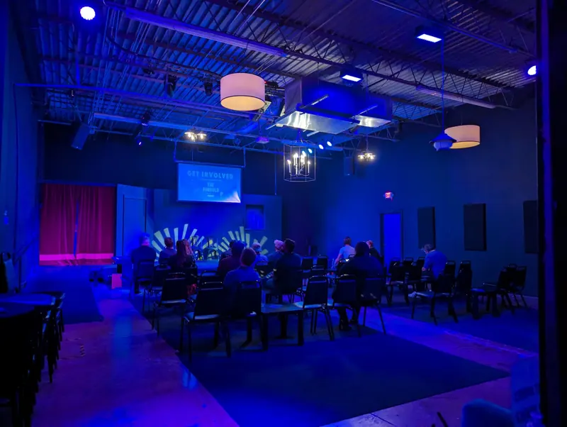 House in deep blue with a yellow sunburst gobo on the stage wall and the audience in their seats