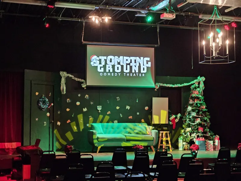Holiday set with a green couch, Christmas tree, and festive color across the stage