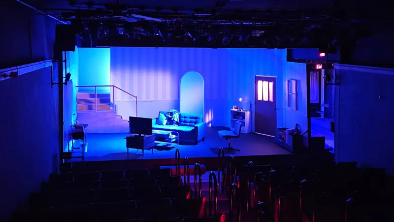 Wide shot of a living-room set in deep blue night wash, house seats in the foreground